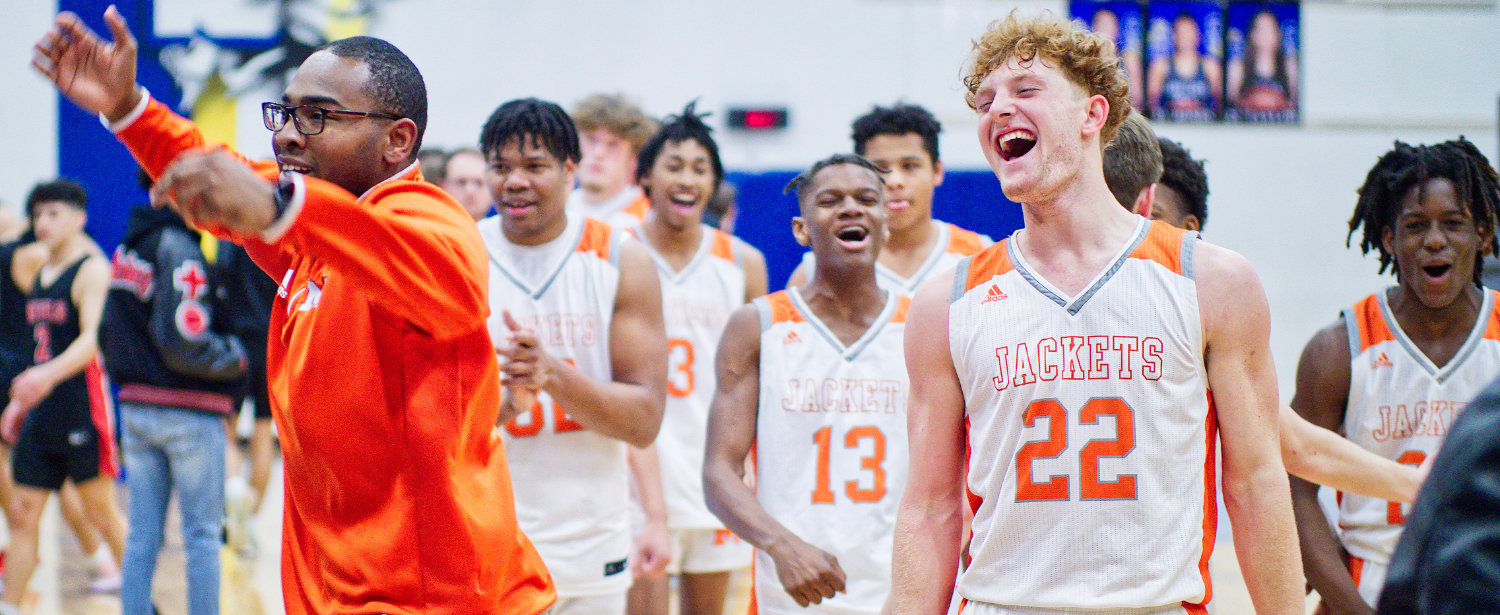 Assistant coach Jaylon Harper, junior forward Dawson Pendergrass and the Mineola Yellowjackets celebrate after their win Friday over Mt. Pleasant Chapel Hill in Sulphur Springs to claim the district title.